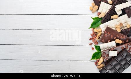 Assortment of chocolate with nuts, cookies and cocoa. On a white wooden background. Top view. Copy space for text. Stock Photo