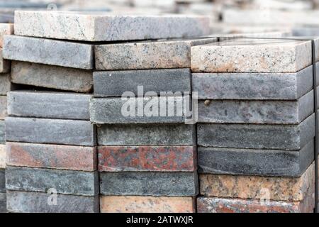 Pieces of white, grey, multicolored granite and marble. Cut into square slabs used for construction and decoration. Stacked in a warehouse for further Stock Photo