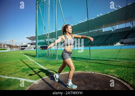 Athlete throwing a disc in a stadium Stock Photo