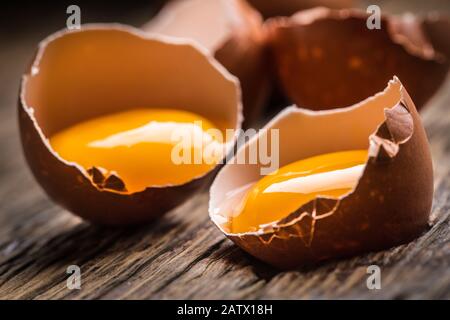 Broken chicken eggs with yolk on wooden table Stock Photo