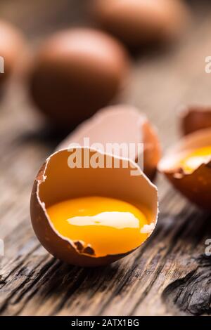 Broken chicken eggs with yolk on wooden table Stock Photo