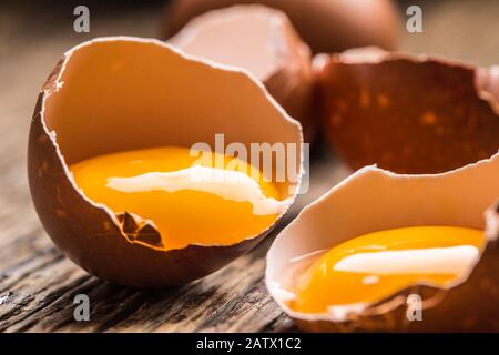 Broken chicken eggs with yolk on wooden table Stock Photo