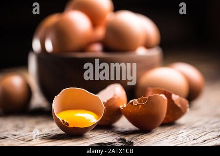 Broken chicken eggs with yolk on wooden table Stock Photo