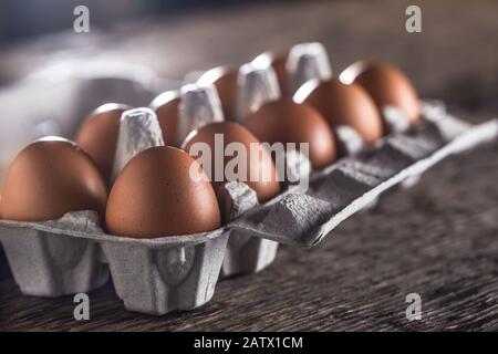 Chicken eggs in carton box on rustic wooden table Stock Photo