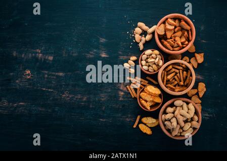 Snack for beer. Salted crackers, chips, nuts, peanuts, pistachios. On a wooden background. Free space for text. Top view. Stock Photo