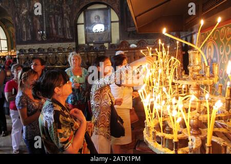 People light candles in St. Sedmochislenitsi church during a big holiday in Sofia, Bulgaria on august 15, 2012. Stock Photo