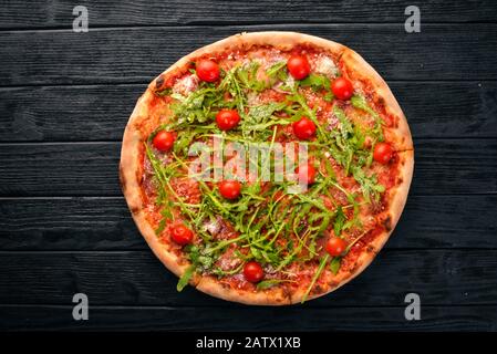 Pizza Primavera. Cherry tomatoes, arugula, cheese. On a wooden background. Top view. Stock Photo