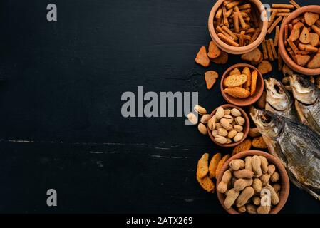 A selection of beer and snacks. Light beer, dark beer, live beer. On a black wooden background. Free space for text. Top view. Stock Photo