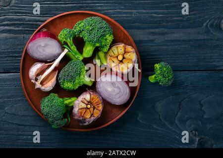 Fresh vegetables on a clay plate. On a wooden background. Top view. Free space for your text. Stock Photo