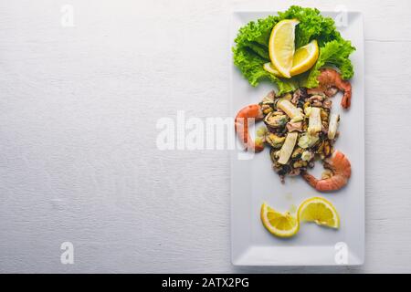 Cold snacks. Seafood, shrimp, mussels, squid, octopus. On a wooden background. Top view. Free space. Stock Photo