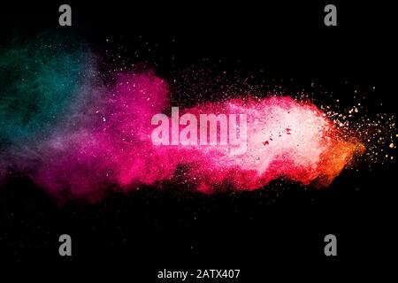 Freeze motion of colored powder explosions isolated on black background.Color dust particle splatter on background. Stock Photo