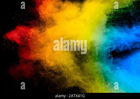 Freeze motion of colored powder explosions isolated on black background.Color dust particle splatter on background. Stock Photo