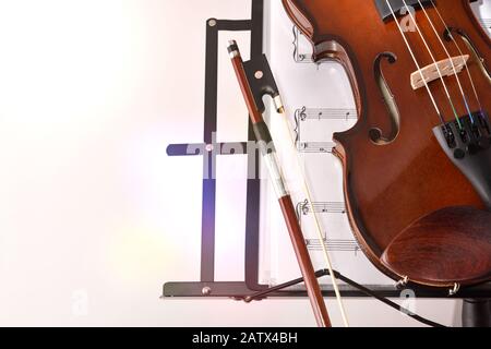Violin on music stand and score on white isolated background. Front view. Horizontal composition. Stock Photo