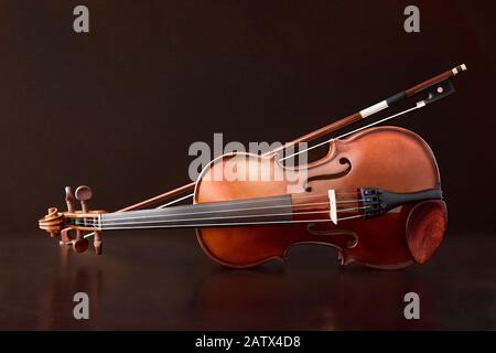 Violin reflected on wooden table and brown gradient background. Horizontal composition. Stock Photo