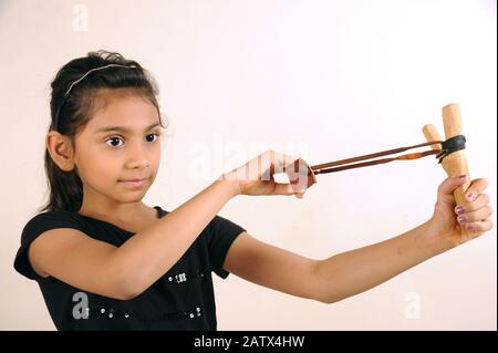 Mumbai, Maharashtra, India- July 22, 2006 - Eight Years Old Indian Little Girl Happy Playing with Traditional Catapult/slingshot on White Background Stock Photo