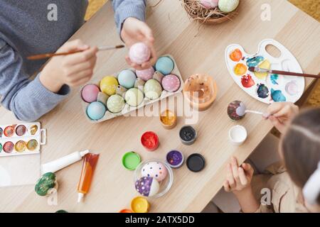Close-up of two children sitting at the table with paints and preparing for Easter they decorating eggs Stock Photo