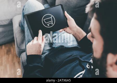 man on couch at home using tablet computer for online shopping Stock Photo