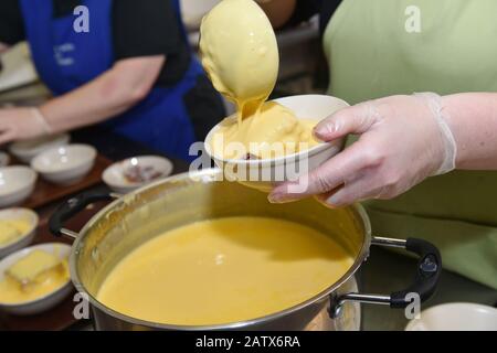 Custard is poured onto a hot pudding in a drop in centre for older people, Leeds UK Stock Photo