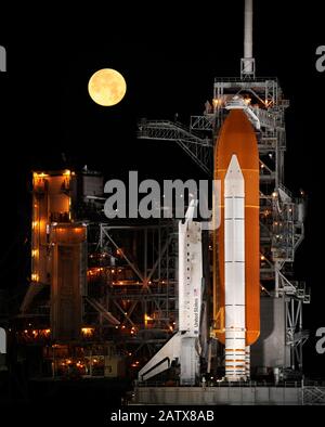 CAPE CANAVERAL, USA - 11 Mar 2009 - A nearly full Moon sets as the space shuttle Discovery ( STS 119 ) sits atop Launch pad 39A at the Kennedy Space C Stock Photo