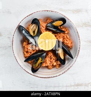 Bulgur with mussels and tomato sauce in a plate. On the old background. Top view. Free space for your text. Stock Photo