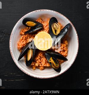 Bulgur with mussels and tomato sauce in a plate. On the old background. Top view. Free space for your text. Stock Photo