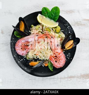 Risotto Rice with vegetables and seafood. Shrimp and mussels. On the old background. Top view. Free space for your text. Stock Photo