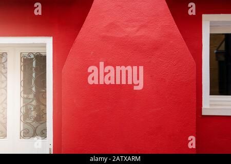 red outdoor wall cement texture with vintage door on abstract background Stock Photo