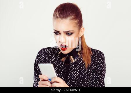 Shocked funny woman with phone. A woman in wonder and irritated holding looking at phone looks desperate at it stunned seeing bad news photos message Stock Photo