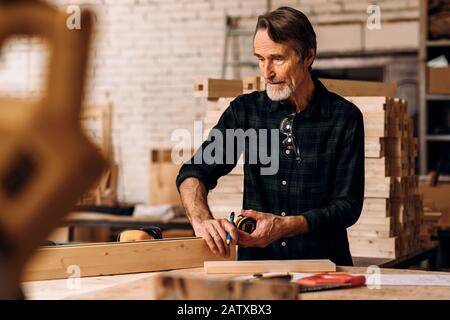 Carpenter measuring piece of wood in workshop Stock Photo