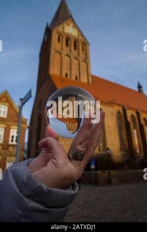 Female hand holding a glass ball in which is shown a scale church. Magic look into the glass globe. View of the world in another perspective. Stock Photo