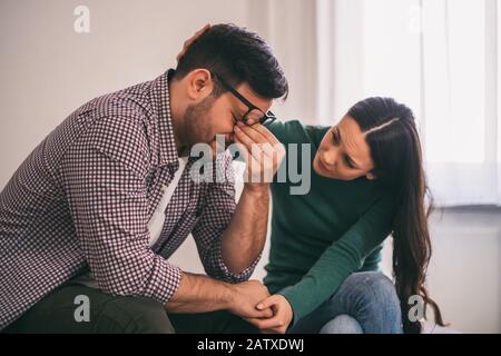 Man is sad and depressed, his wife is consoling him. Stock Photo