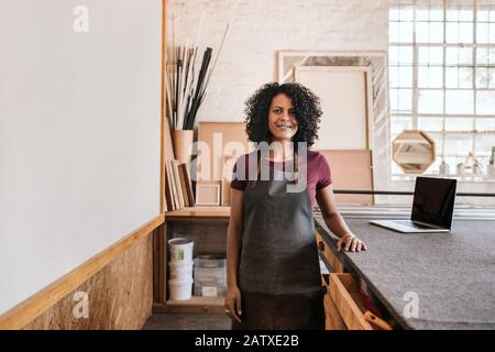 Smiling young woman standing in her framing studio Stock Photo