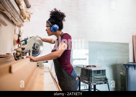 Female artisan cutting wood in her framing studio Stock Photo