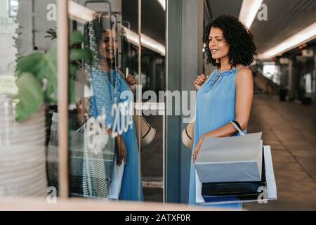 Smiling young woman window shopping in a mall Stock Photo