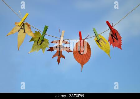 string with leaves and letters spelling: AUTUMN in front of blue sky Stock Photo