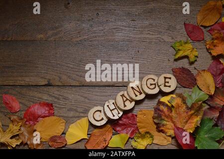 changing colorful leaves on wooden planks and pieces of wood with the letters spelling CHANGE burnt into them Stock Photo