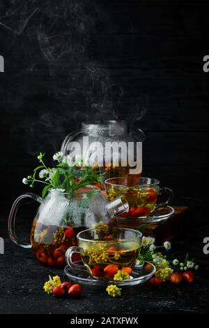 Chamomile and wild rose tea. Hot winter drinks. On a black background. Top view. Stock Photo