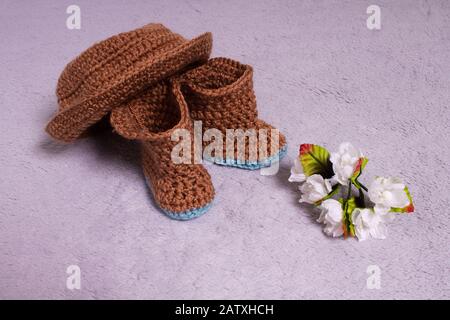 Knitted hat and boots. Knitted shoes and clothes. Booties for babies. Made by hands. Crochet Stock Photo