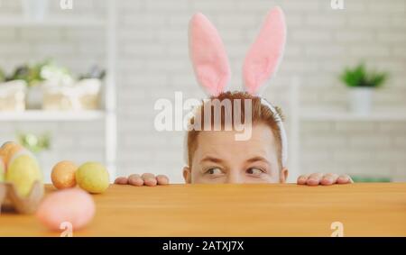 Happy easter.A funny fat man decorates eggs while sitting at a table with Easter decor in the background Stock Photo