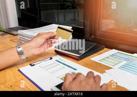Businessman holding credit card and using smartphone. Making payment while online shopping. E-commerce and modern technology concept. Stock Photo