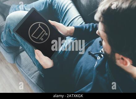 high angle view of man on couch at home using tablet computer for online shopping Stock Photo