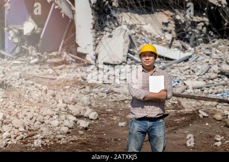 Engineer holding tablet is checking for destruction, demolishing building. Stock Photo