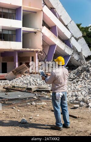 Engineer holding tablet is checking for destruction, demolishing building. Stock Photo