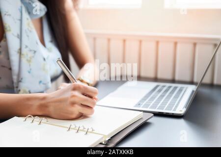 Close up of Woman's hands and writing on notebook in cafe. Stock Photo