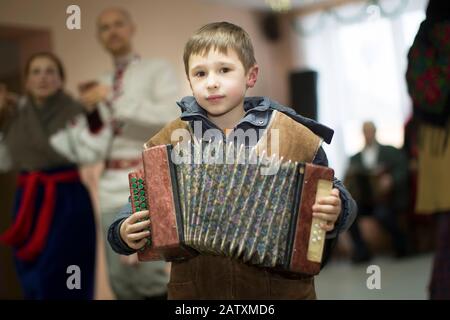 Rite of a generous evening. Kalyada ceremony. Village child with Russian accordion Stock Photo