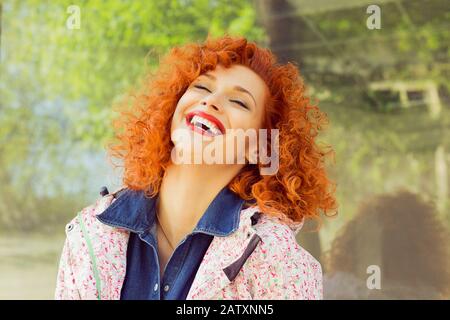 Beautiful red curly hair woman laughing, isolated outside. Happiness. Positive human emotion facial expression. Stock Photo