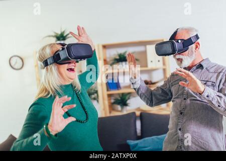 Senior couple having fun with virtual reality glasses. Stock Photo