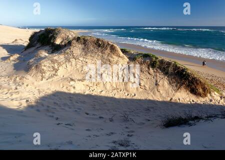 Couple walking along the beach next to the towering sand dunes of Sardinia Bay near Port Elizabeth, Eastern Cape, South Africa Stock Photo