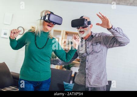 Senior couple having fun with virtual reality glasses. Stock Photo