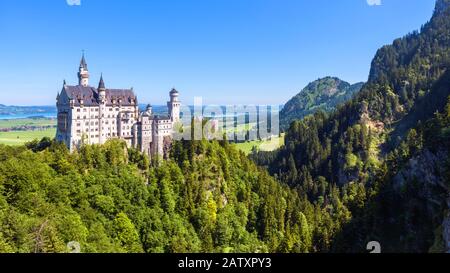 Neuschwanstein castle in mountains, Bavaria, Germany. It is a famous landmark of German Alps. Landscape with forest and Neuschwanstein castle in summe Stock Photo